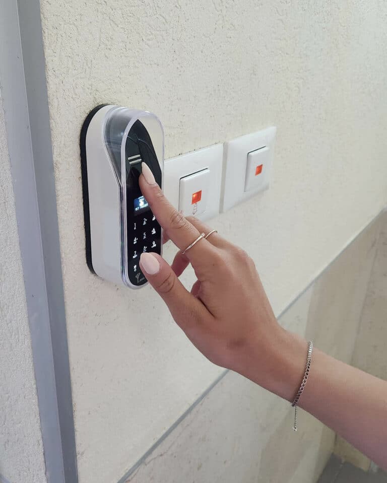 Entr מערכת נעילה חכמה 6 Fingerprint and touch code of an entr smart lock. Unit on the wall. A woman opens a door with a fingerprint.